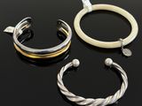 three different bracelets and a ring on a black surface