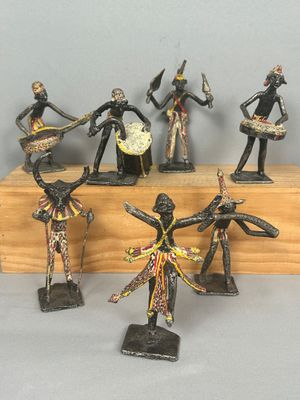 cinq figurines représentant des danseurs africains, posées sur un socle en bois