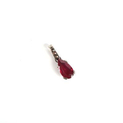 un petit bijou rouge sur une surface blanche