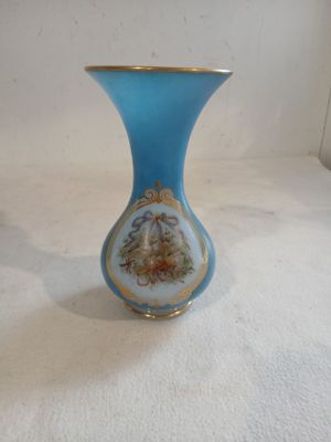 a blue vase with a gold rim on a white surface