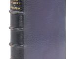 un vieux livre à la couverture noire posé sur une surface blanche