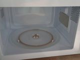 a white microwave with a lid on it on a wooden floor