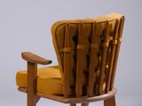 the chair is made of wood and has a mustard colored upholstered seat