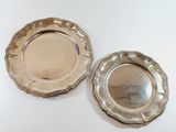 two silver plated dishes on a white surface