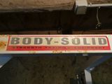 une vieille enseigne sur laquelle on peut lire « Body Solid – Appareils de musculation »