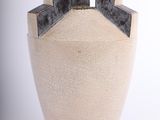un vase blanc surmonté d'un couvercle noir, posé sur une surface blanche