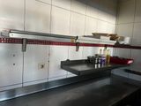 une cuisine équipée de plans de travail en inox et d'une étagère en métal