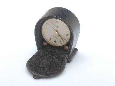 une petite horloge noire posée sur une table blanche