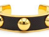 un gros plan d'un bracelet orné de boules dorées sur fond blanc