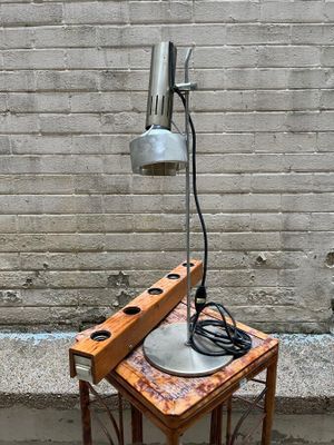a small table with a lamp on it next to a brick wall