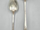 two silver spoons and a spoon on a white surface