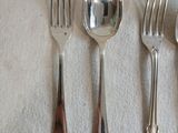 quatre cuillères en argent et deux cuillères en argent posées sur une nappe blanche