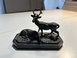 une statue représentant un cerf et un cerf couché sur une table
