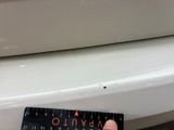 a person that is holding a ruler in front of a toilet