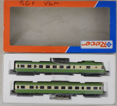 deux wagons verts et blancs se trouvent dans une boîte posée sur une surface blanche