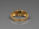 an image of a close up of a gold ring with a green stone