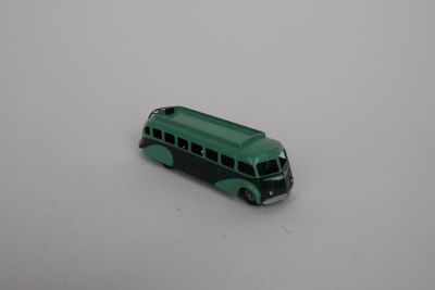 a green toy bus that is sitting on a white surface