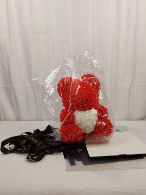 un ours en peluche rouge assis sur un drap blanc
