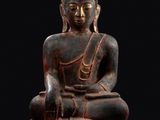 une statue de Bouddha assis sur un socle en bois