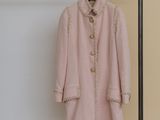 a pink coat hanging on a clothes rack in a room