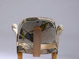 a chair that has a wooden leg and a seat with a bird print on it