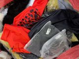 a cat that is laying on a bed with clothes in it