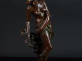une statue en bronze d'une femme assise sur un rocher