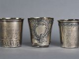 three silver shot glasses sitting next to each other on top of a table