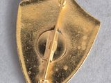 a gold pin with a knife on it