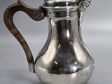 a silver coffee pot with a wooden handle on a table