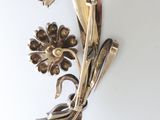 a silver brooch with flowers on it on a white surface