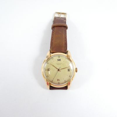 une image représentant une montre en or avec un bracelet marron sur un fond blanc