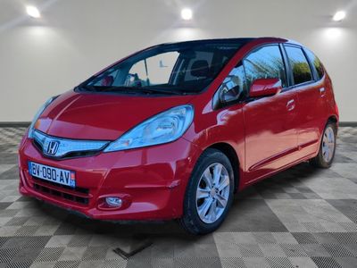 the red honda fit is parked in a large room