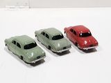 three toy cars sitting next to each other on a white surface