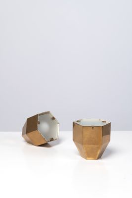 deux vases dorés et blancs posés sur une table blanche