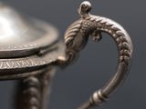 a close up of a silver cup with a handle on a table