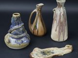 trois vases et un morceau de bois sont posés sur une surface noire