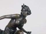 bronze statue of a woman sitting on a rock with her hands in the air