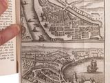 someone is holding an open book with a picture of a city in it