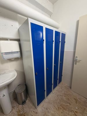 une salle de bains équipée de casiers bleus et d'un lavabo