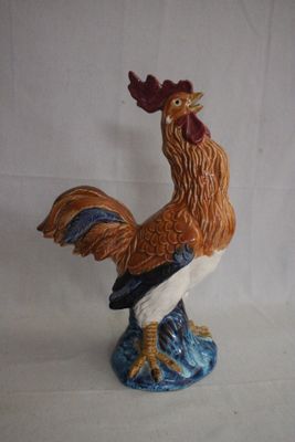 une figurine représentant un coq debout sur un rocher
