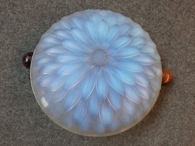 a glass bowl with a flower on it on the floor