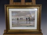 tableau représentant un groupe de personnes marchant sur une plage, posé sur un chevalet en bois