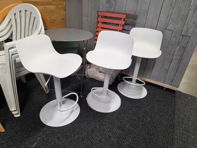 trois chaises blanches et une table dans une pièce