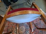 a wooden chair with a red seat on a rug