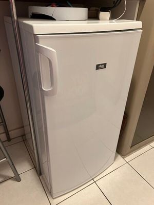 un petit réfrigérateur blanc dans le coin d'une cuisine