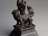 a bronze statue of a woman on a horse with a basket on its head