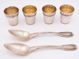 four silver cups and spoons sitting next to each other on a white surface