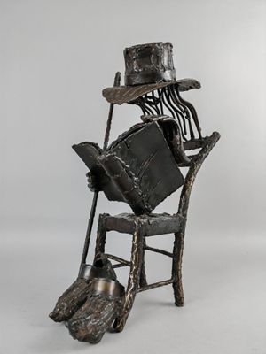 statue représentant un homme assis sur une chaise, coiffé d'un chapeau