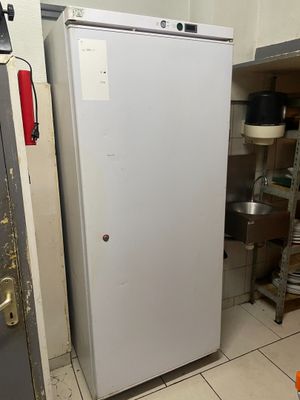 un réfrigérateur blanc qui se trouve dans une cuisine, à côté d'une étagère